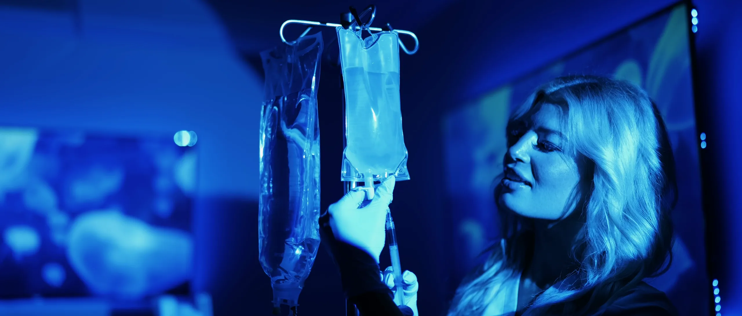 Still from the Neuregen brand film: a clinician checks an IV line in a softly lit treatment room.